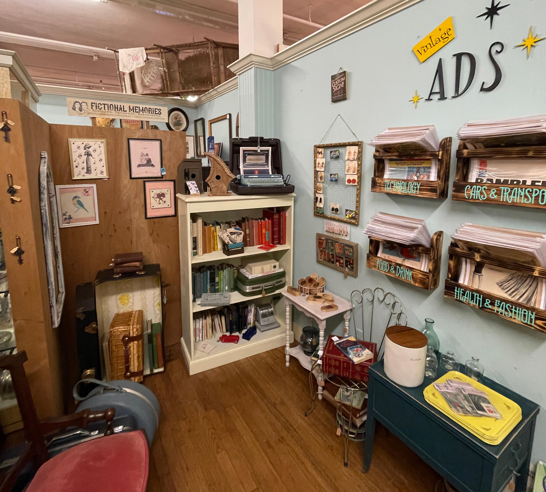 an antique and craft booth full of ads, furniture, books, and more, inside of a store called Marina Marina in the Marietta square